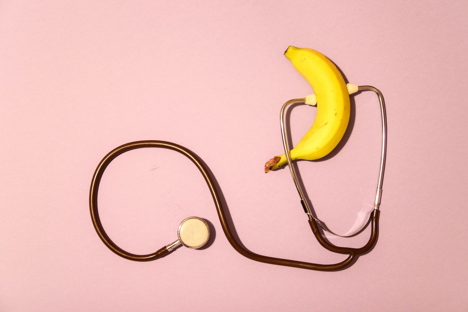 A Banana and a Stethoscope on a Pink Surface