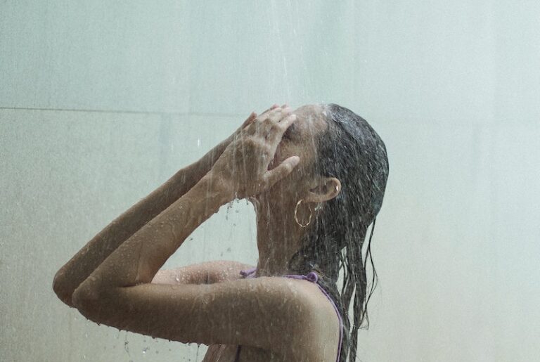Sensual woman in bikini under stream in shower